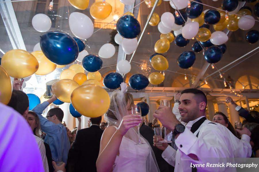 People dancing at wedding with white blue and gold balloons